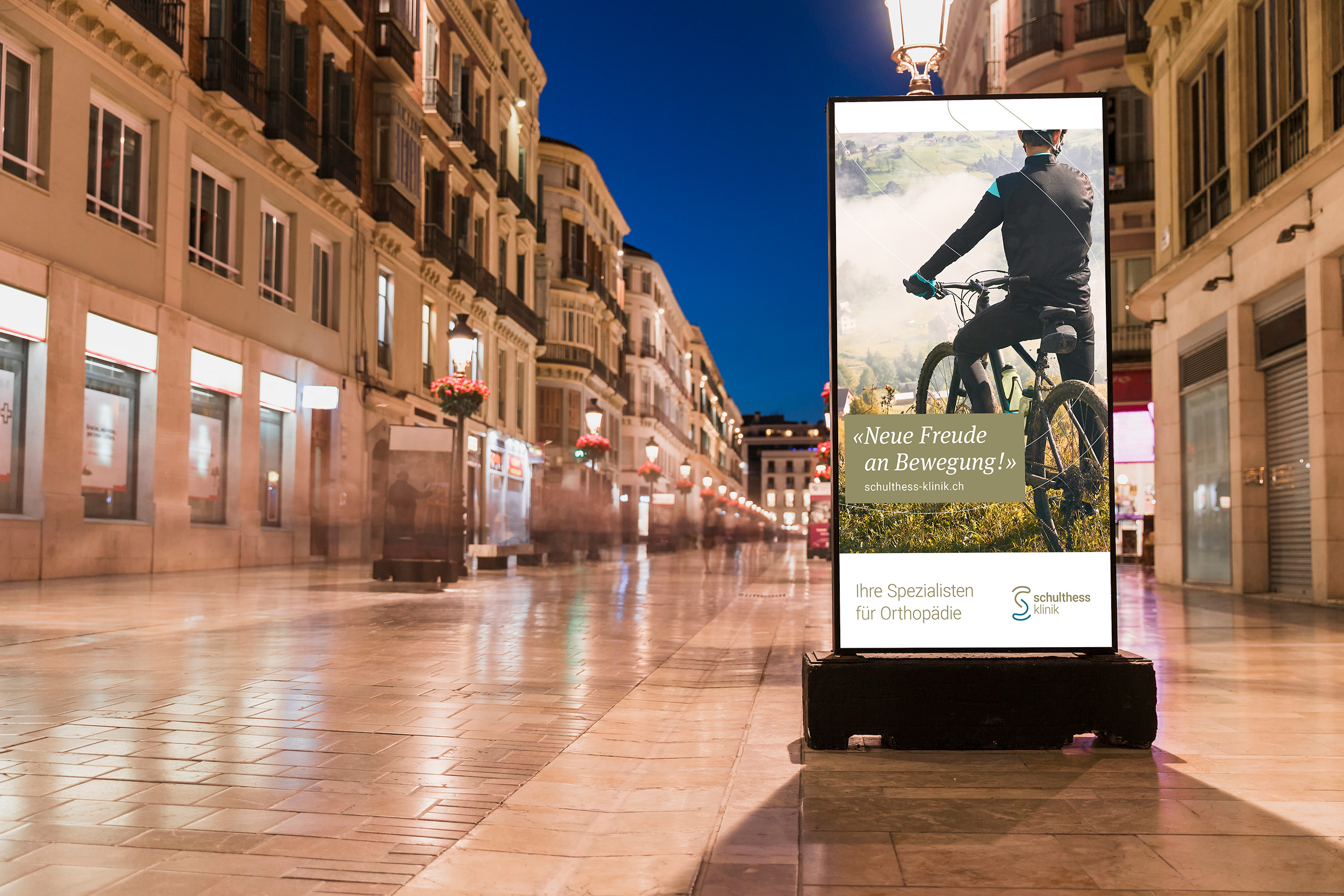 Schulthess Klinik Plakat mit Fahrrad in der Stadt bei Nacht
