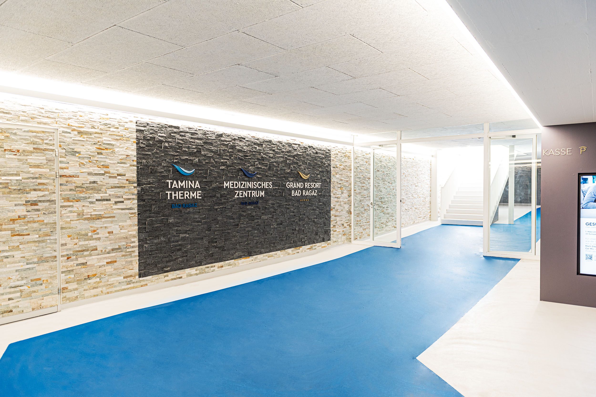 Eingangsbereich Tamina Therme mit Wandverblendung aus Naturstein und blauer Bodenbeschichtung