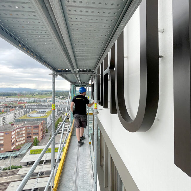 Montage der Fassadenbeschriftung für das Hochaus «Oerlikon One» auf Gerüst im 23. Stock