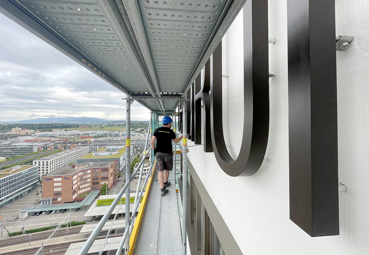 Montage der Fassadenbeschriftung für das Hochaus «Oerlikon One» auf Gerüst im 23. Stock