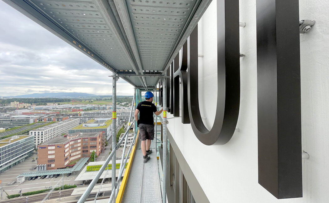 Montage der Fassadenbeschriftung für das Hochaus «Oerlikon One» auf Gerüst im 23. Stock